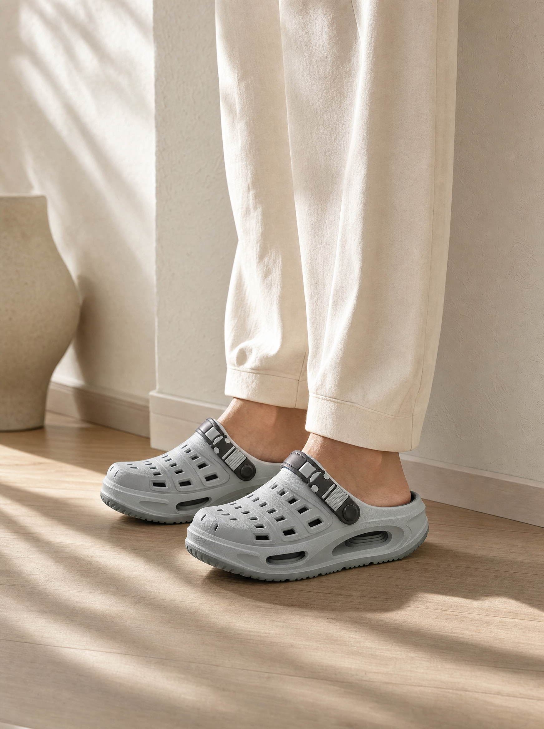 Grey clogs worn on bare feet on an oak floor